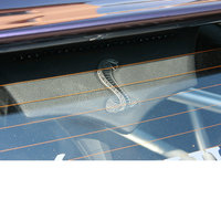 Ein verzierter, lederner Sonnenschutz hinter der Heckscheibe eines Autos